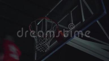 特写职业篮球运动员在泛光篮球场篮球比赛中扣篮的形象..
